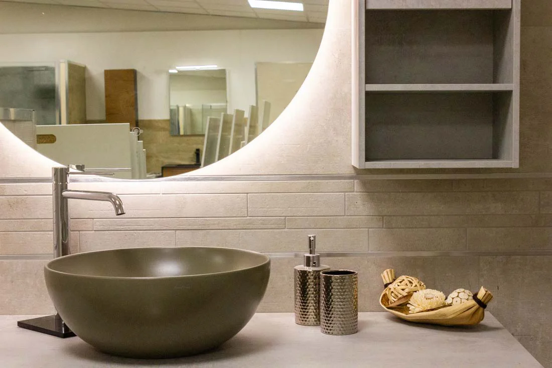 Lavabo da appoggio con specchio circolare illuminato e rivestimento materico